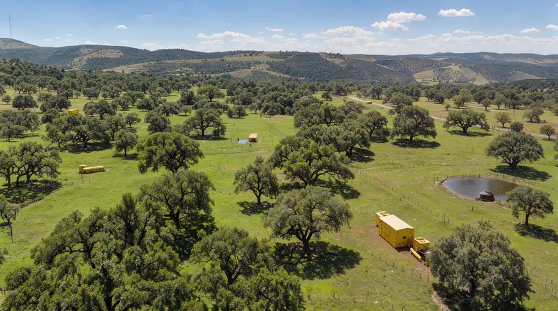 Aerial view of Hill Country ranch land with live oaks and a stock tank, land clearing in Hill Country, Texas