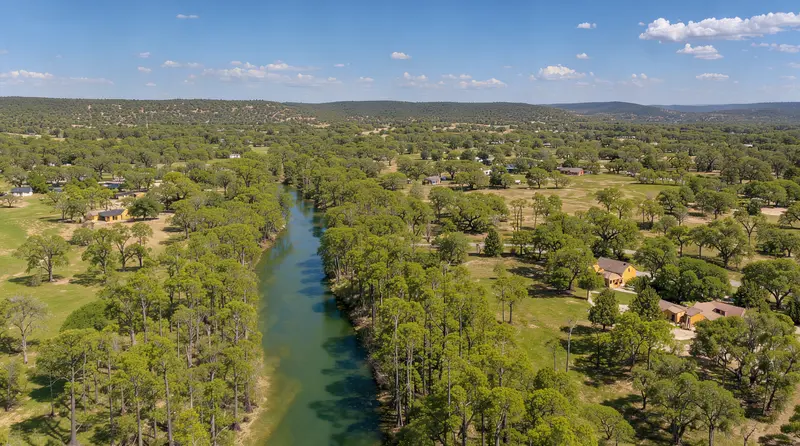 Aerial view of a river valley with wooded homesites, land clearing in Travis County, Texas