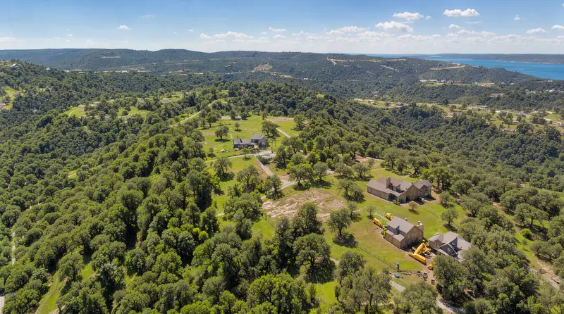 Aerial view of wooded hills with homes on acreage, land clearing in Leander, TX